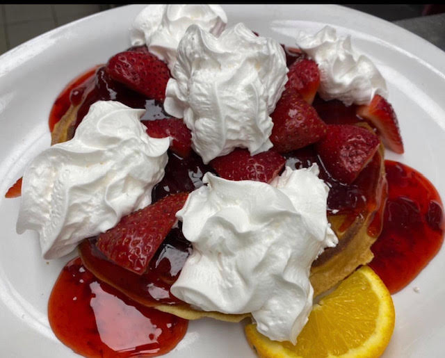 Belgian waffles covered in fruit and whipped cream